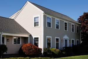 A two story beige house on a sunny day.